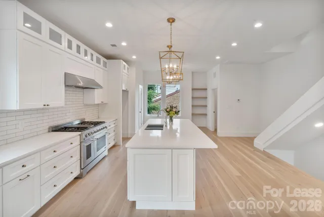 a kitchen with stainless steel appliances granite countertop a sink a stove a refrigerator and a oven