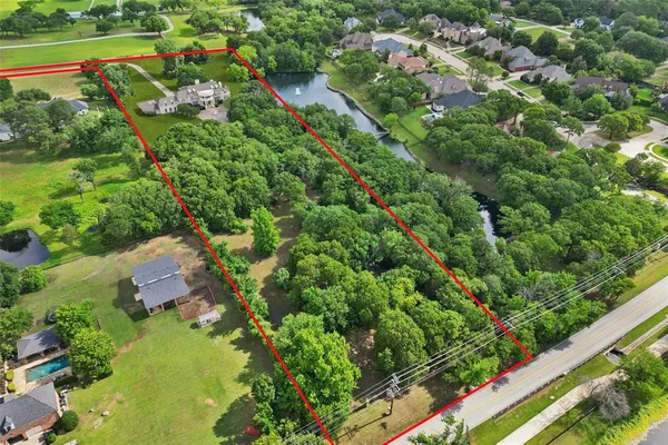 an aerial view of residential houses with outdoor space and trees all around