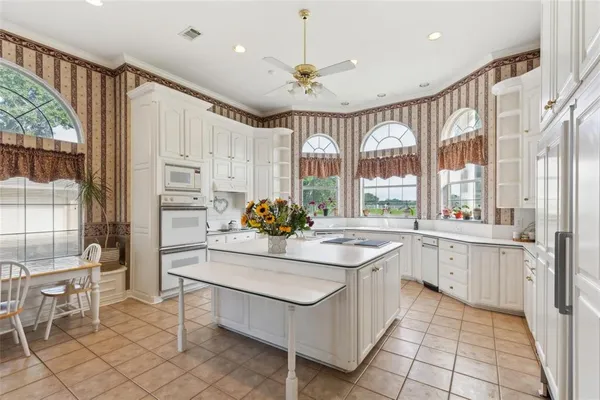 a large white kitchen with granite countertop a stove a sink dishwasher and a refrigerator with wooden floor