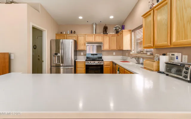 a kitchen with stainless steel appliances kitchen island granite countertop a refrigerator a sink a stove with wooden cabinets