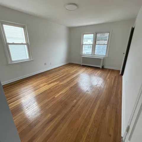 a view of an empty room with wooden floor and window