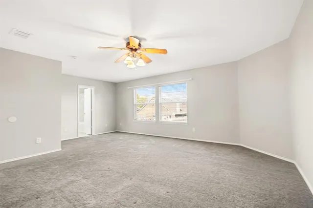 an empty room with windows and chandelier fan