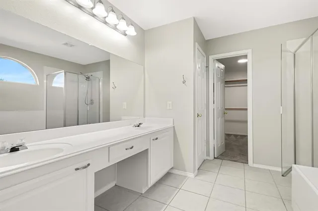 a spacious bathroom with a double vanity sink mirror and bathtub