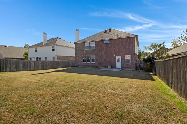 a view of a house with backyard and tall trees