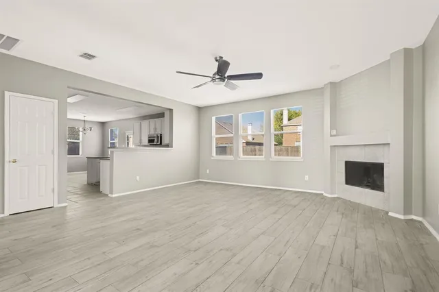 a view of a livingroom with wooden floor a ceiling fan and windows