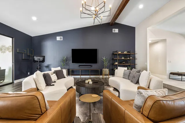 a living room with furniture a flat screen tv and kitchen view