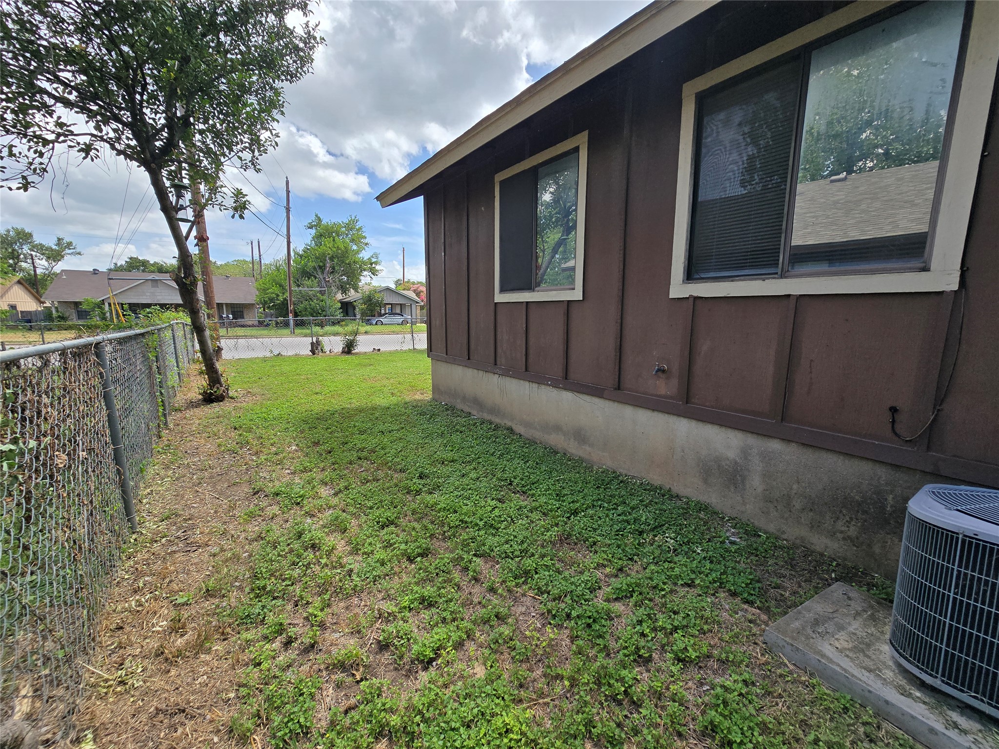 6206 Buffalo Pass, Unit A Austin, TX 78745 - Photo 21 of 24 A modest home with chain link fencing encloses the side yard, offering a functional outdoor area.