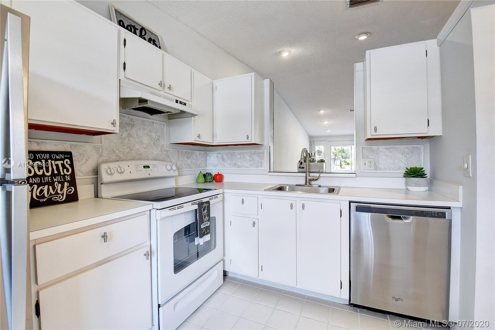 8617 Sunbird Place, Unit B Boca Raton, FL 33496 - Photo 4 of 41 a kitchen with white cabinets and white appliances