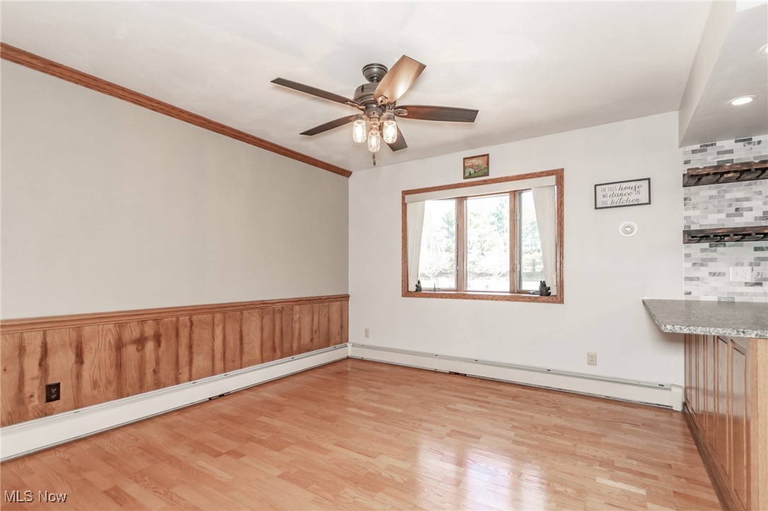 2866 South County Line Road Madison, OH 44057 - Photo 26 of 48 Unfurnished room with light wood-type flooring, wainscoting, a baseboard radiator, and ceiling fan