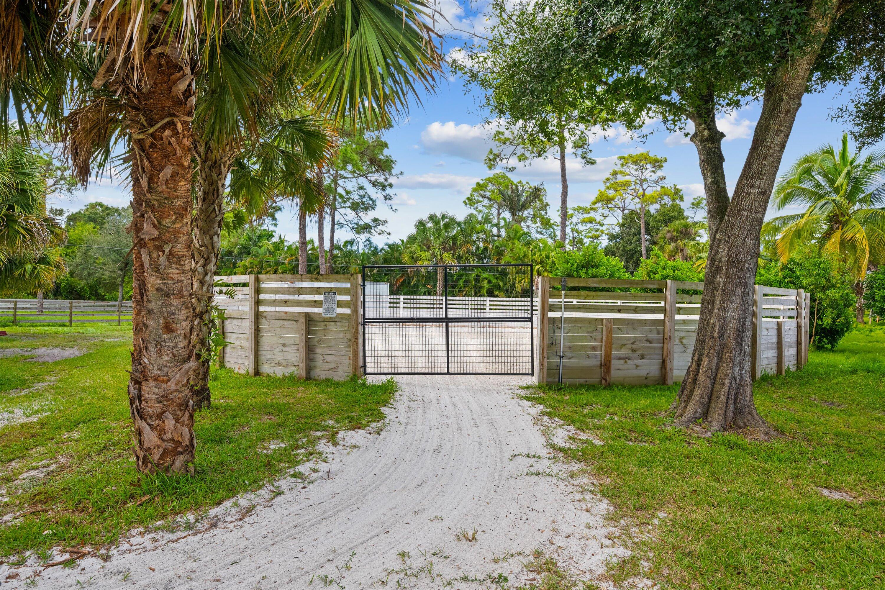 3509 C Road, Unit BARN Loxahatchee Groves, FL 33470 - Photo 8 of 12 a view of a backyard with large trees and a small yard