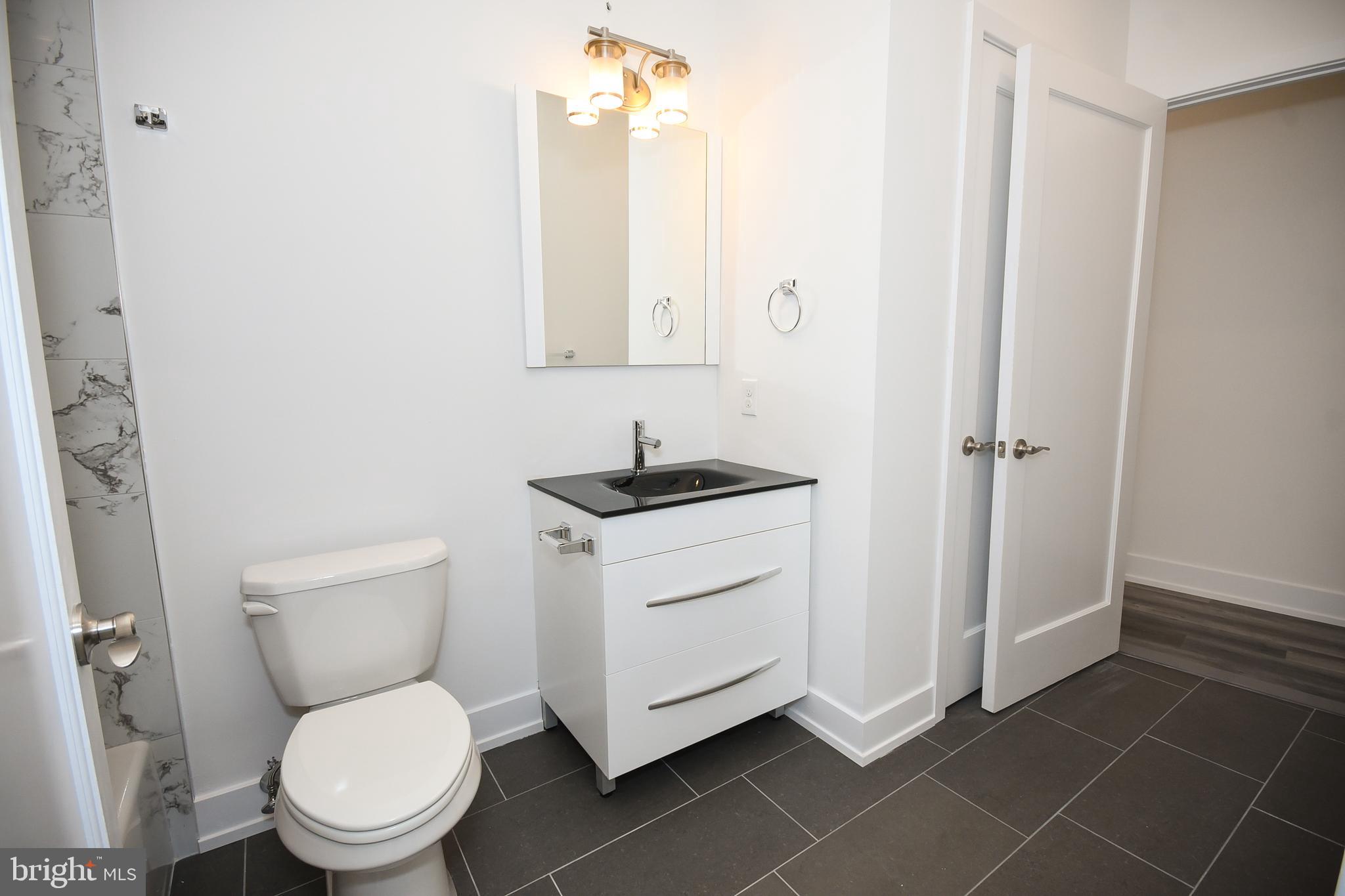 6164-66 Ridge Avenue, Unit 301 Philadelphia, PA 19128 - Photo 4 of 8 a white toilet sitting next to a bathroom sink