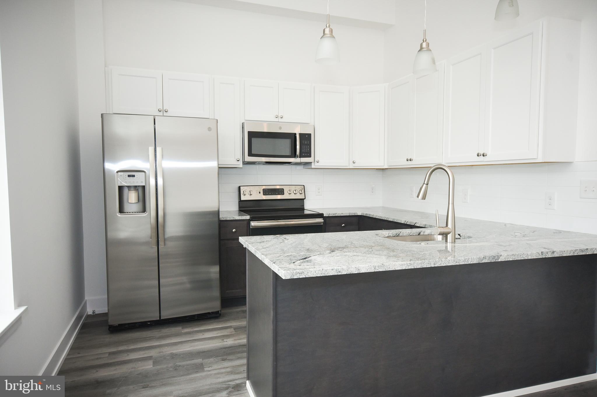 6164-66 Ridge Avenue, Unit 301 Philadelphia, PA 19128 - Photo 8 of 8 a kitchen with stainless steel appliances granite countertop a refrigerator a sink and white cabinets