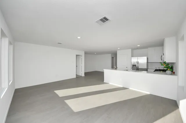 a view of a kitchen with kitchen island a refrigerator wooden floor and a sink