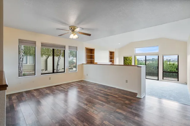 a view of an empty room with a window and wooden floor