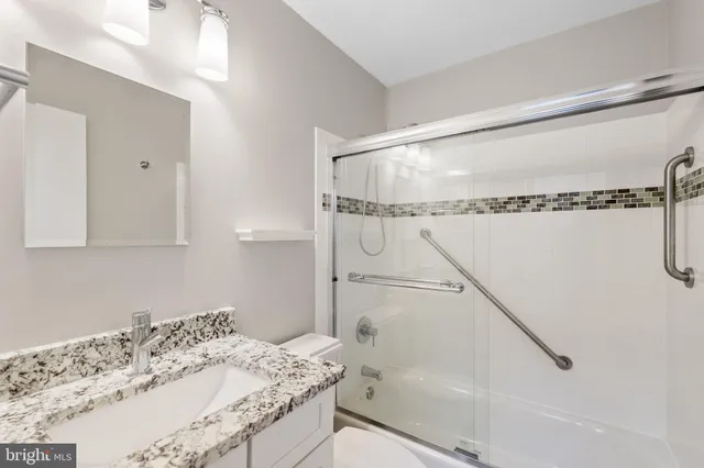 a bathroom with a granite countertop sink a mirror and shower