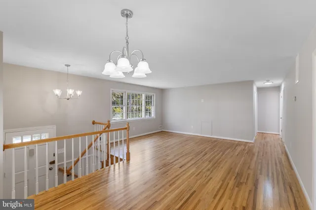 a view of a room with wooden floor chandelier and windows