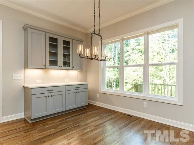 6920 Ray Family Farm Court, Unit LT20 Raleigh, NC 27613 - Photo 9 of 22 a kitchen with granite countertop a stove and white cabinets with wooden floor