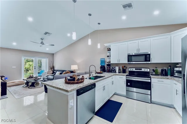 a kitchen with stainless steel appliances granite countertop a sink dishwasher stove and white cabinets with wooden floor