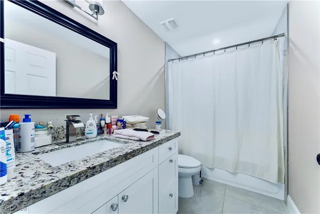 a bathroom with a granite countertop sink a toilet and a mirror