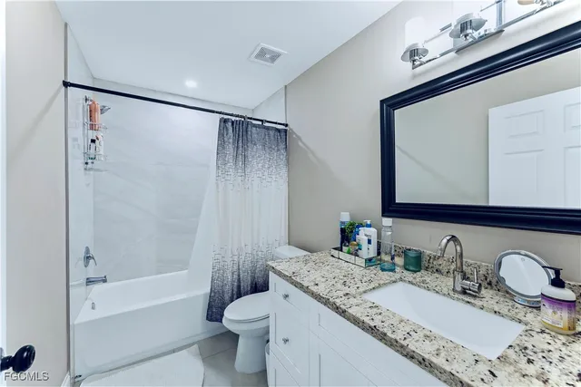 a bathroom with a granite countertop sink mirror vanity and toilet