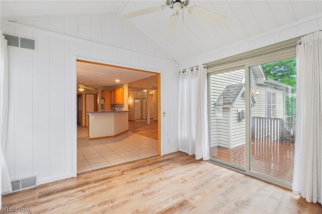 7007 Clingan Road, Unit 85 Youngstown, OH 44514 - Photo 24 of 46 Vaulted white panel ceiling with ceiling fan, wood-finish flooring, and sliding glass door access to an exterior deck