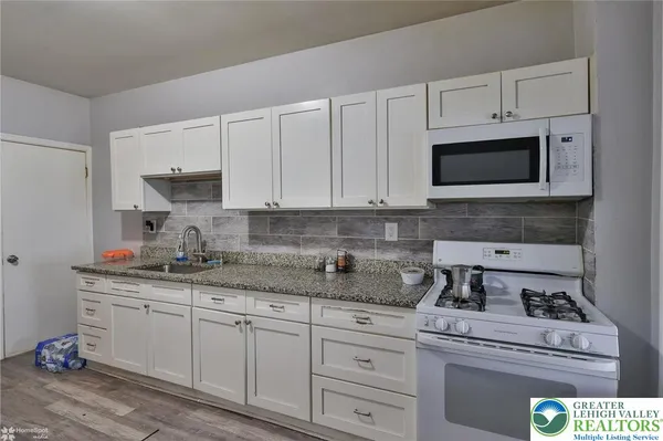 a kitchen with granite countertop white cabinets and white appliances