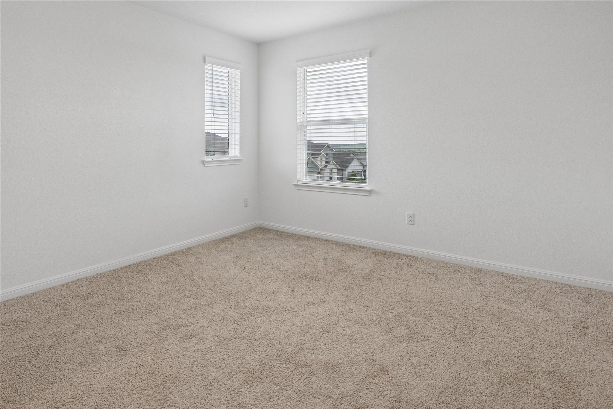 6407 Rounded Pebble Lane Buda, TX 78610 - Photo 21 of 32 Two windows with blinds illuminate a spacious, carpeted room.
