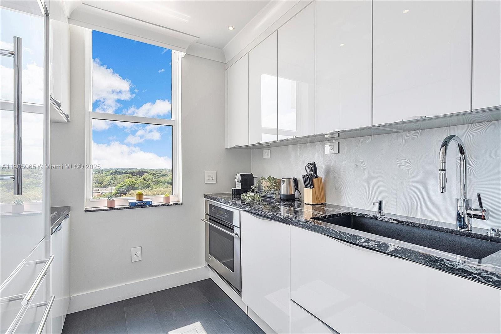 2889 McFarlane Road, Unit 902 Miami, FL 33133 - Photo 37 of 62 a kitchen with granite countertop white cabinets and white appliances