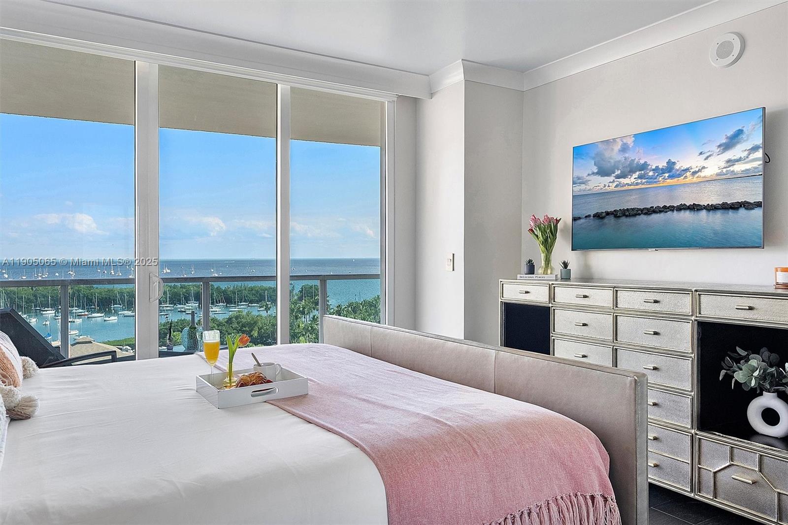 2889 McFarlane Road, Unit 902 Miami, FL 33133 - Photo 42 of 62 a bedroom with a bed a large window and a flat tv screen