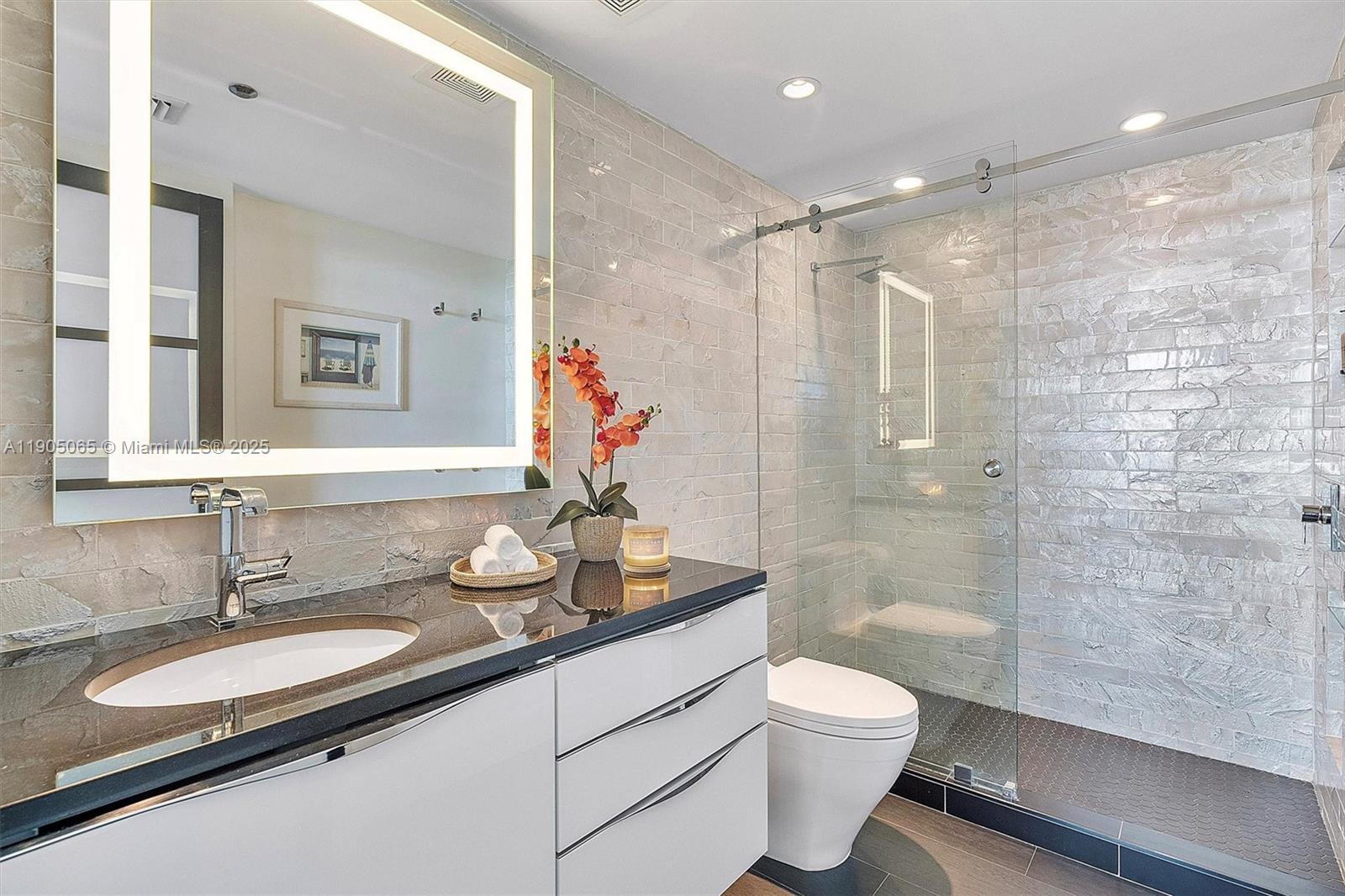 2889 McFarlane Road, Unit 902 Miami, FL 33133 - Photo 48 of 62 a bathroom with a granite countertop sink toilet a mirror and shower