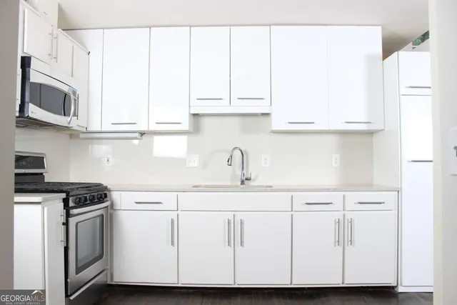 a kitchen with stainless steel appliances granite countertop white cabinets and a sink