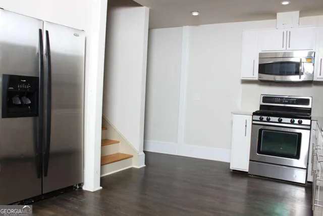 a kitchen with granite countertop a refrigerator and a stove top oven