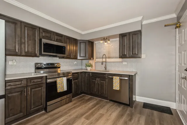 a kitchen with stainless steel appliances granite countertop wooden cabinets a stove top oven a sink and dishwasher