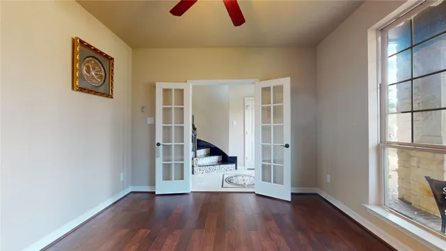 a view of an empty room with wooden floor and fan