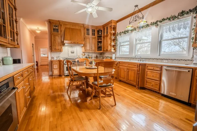 a dining hall with stainless steel appliances granite countertop a stove a refrigerator a dining table and chairs with wooden floor