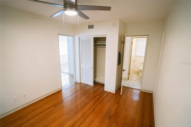 an empty room with wooden floor a ceiling fan and staircase