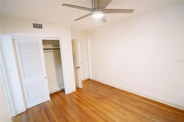 an empty room with wooden floor and ceiling fan