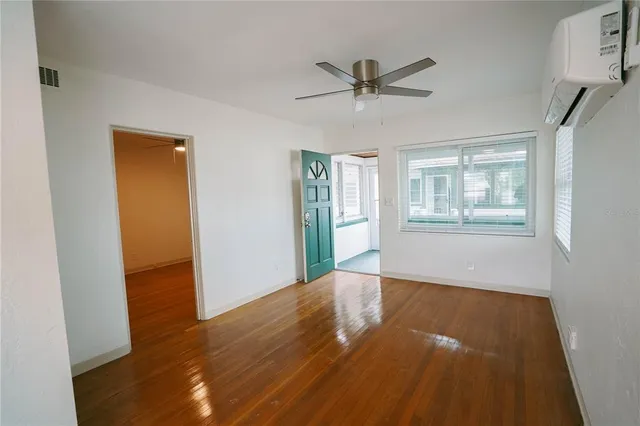 a view of empty room with wooden floor and fan