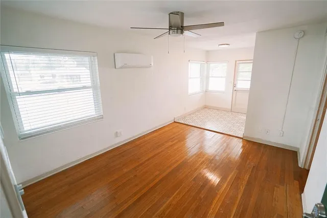 a view of empty room with wooden floor and fan