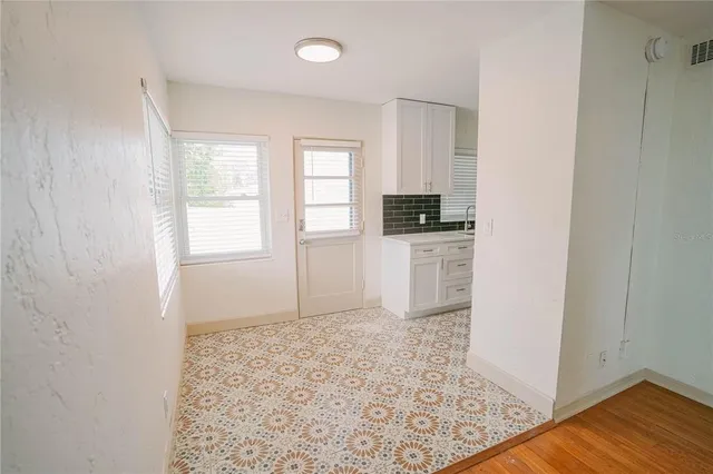 an empty room with wooden floor cabinet and windows