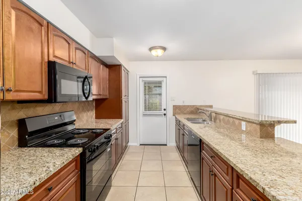 a kitchen with stainless steel appliances granite countertop a refrigerator a stove and a sink