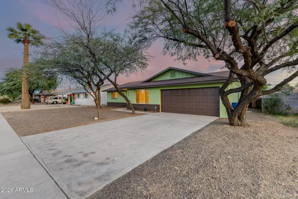 a view of a house with a yard and a large tree
