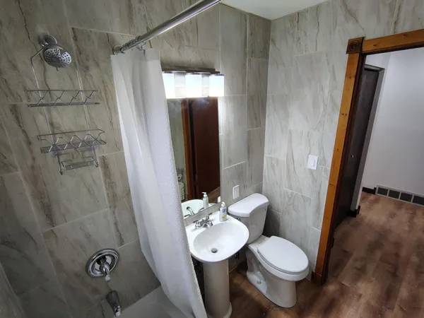 a bathroom with a sink a toilet a mirror and shower