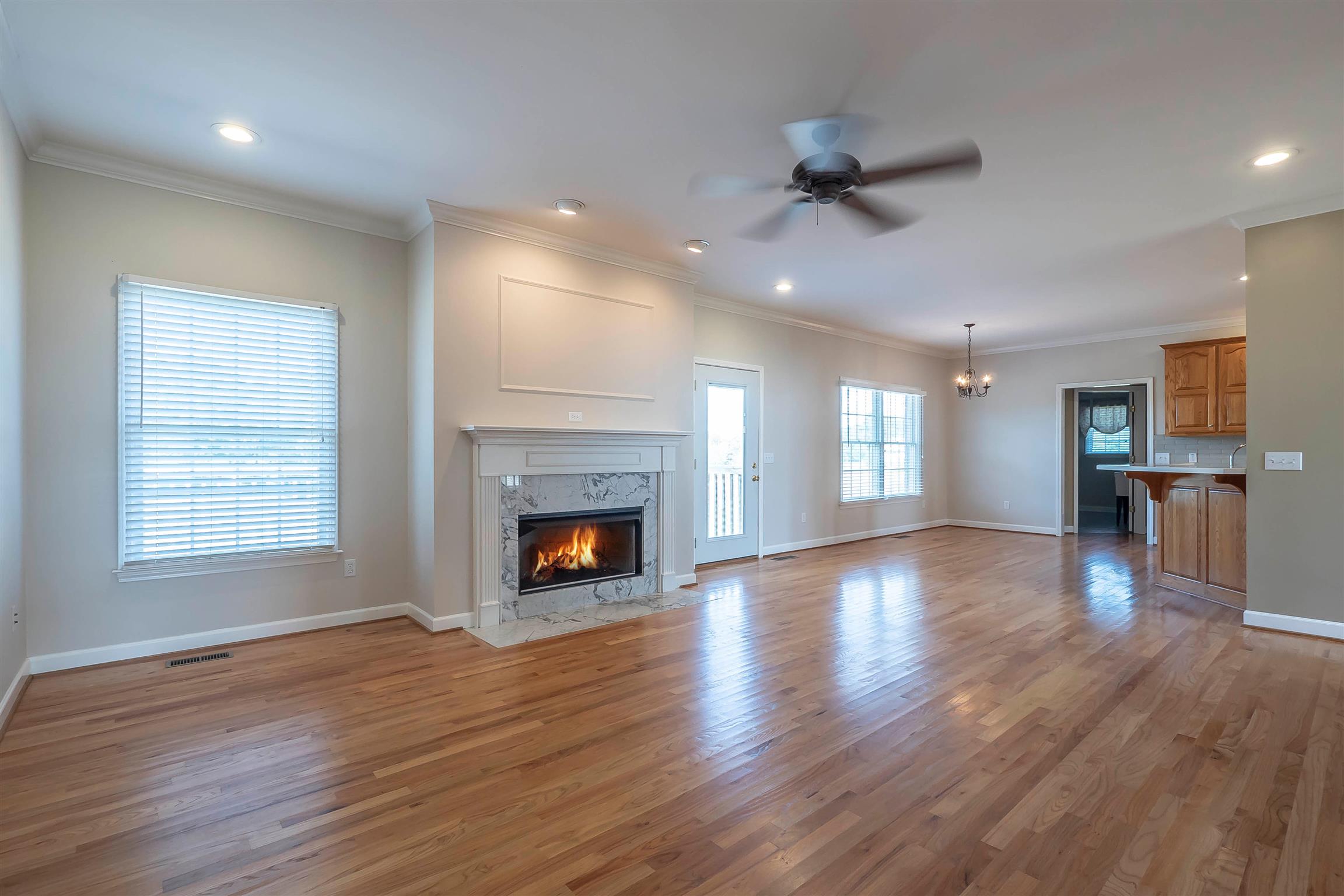 7722 Barnhill Road Primm Springs, TN 38476 - Photo 15 of 30 an empty room with wooden floor a ceiling fan and kitchen view