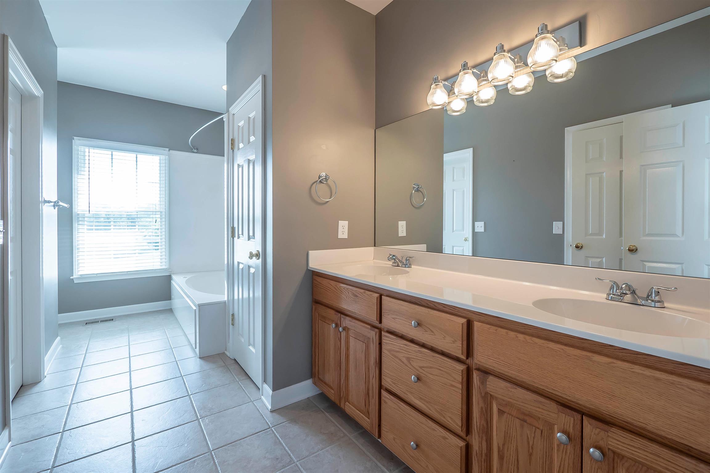 7722 Barnhill Road Primm Springs, TN 38476 - Photo 20 of 30 a spacious bathroom with a double vanity sink a toilet a mirror and a shower