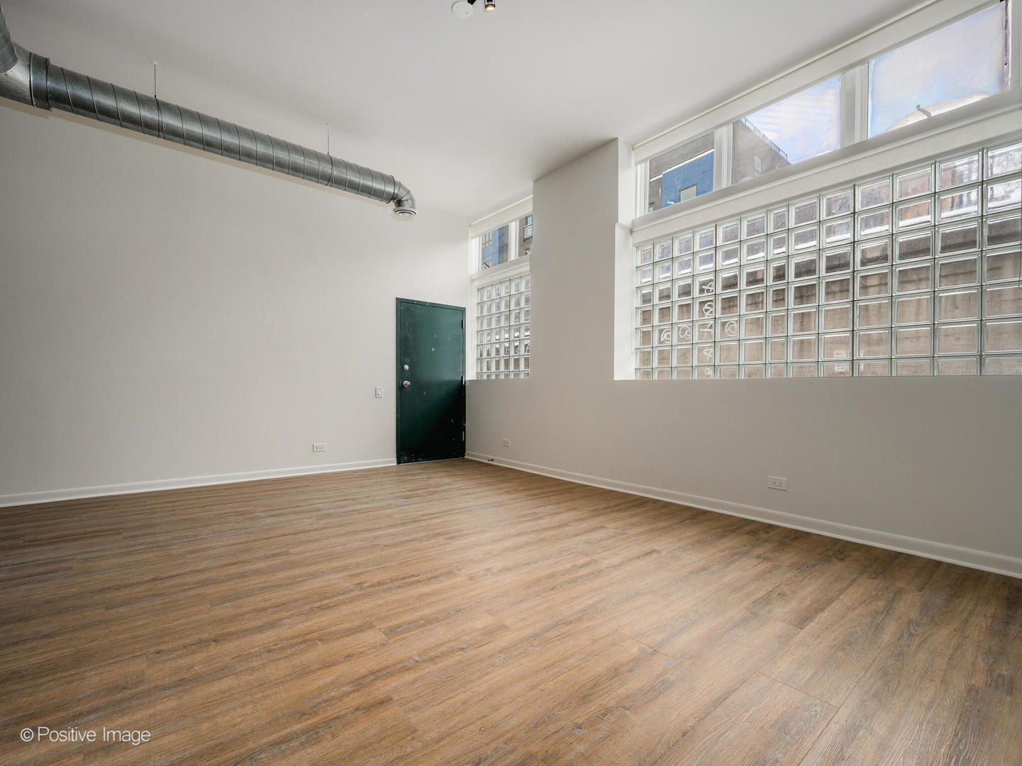 2418 West Bloomingdale Avenue, Unit 102 Chicago, IL 60647 - Photo 4 of 14 a view of an empty room with wooden floor and a window