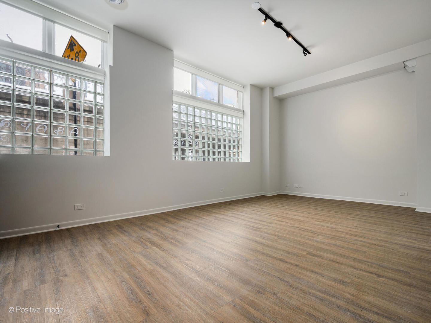 2418 West Bloomingdale Avenue, Unit 102 Chicago, IL 60647 - Photo 5 of 14 a view of an empty room with a window and wooden floor