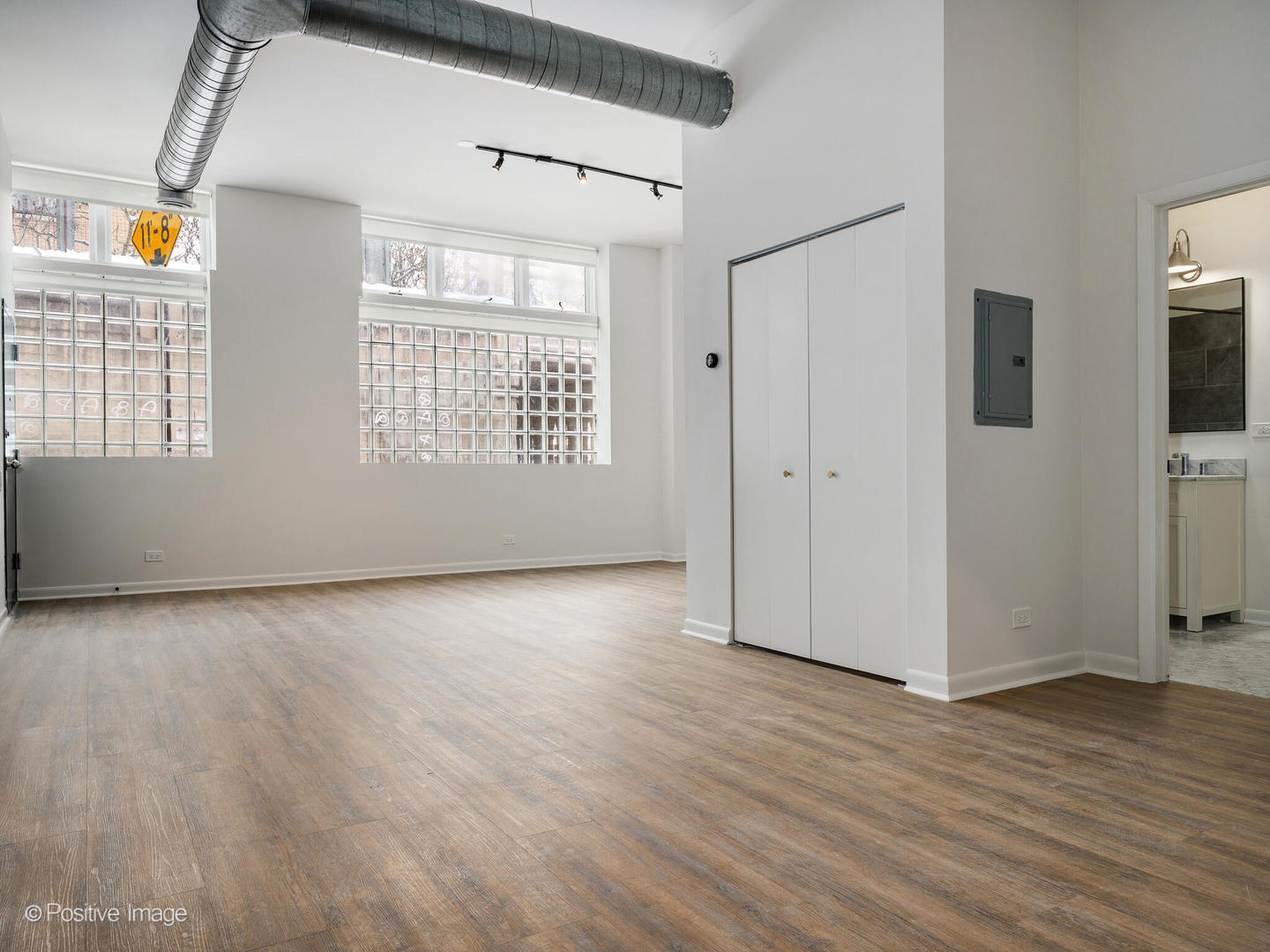 2418 West Bloomingdale Avenue, Unit 102 Chicago, IL 60647 - Photo 7 of 14 an empty room with wooden floor and windows