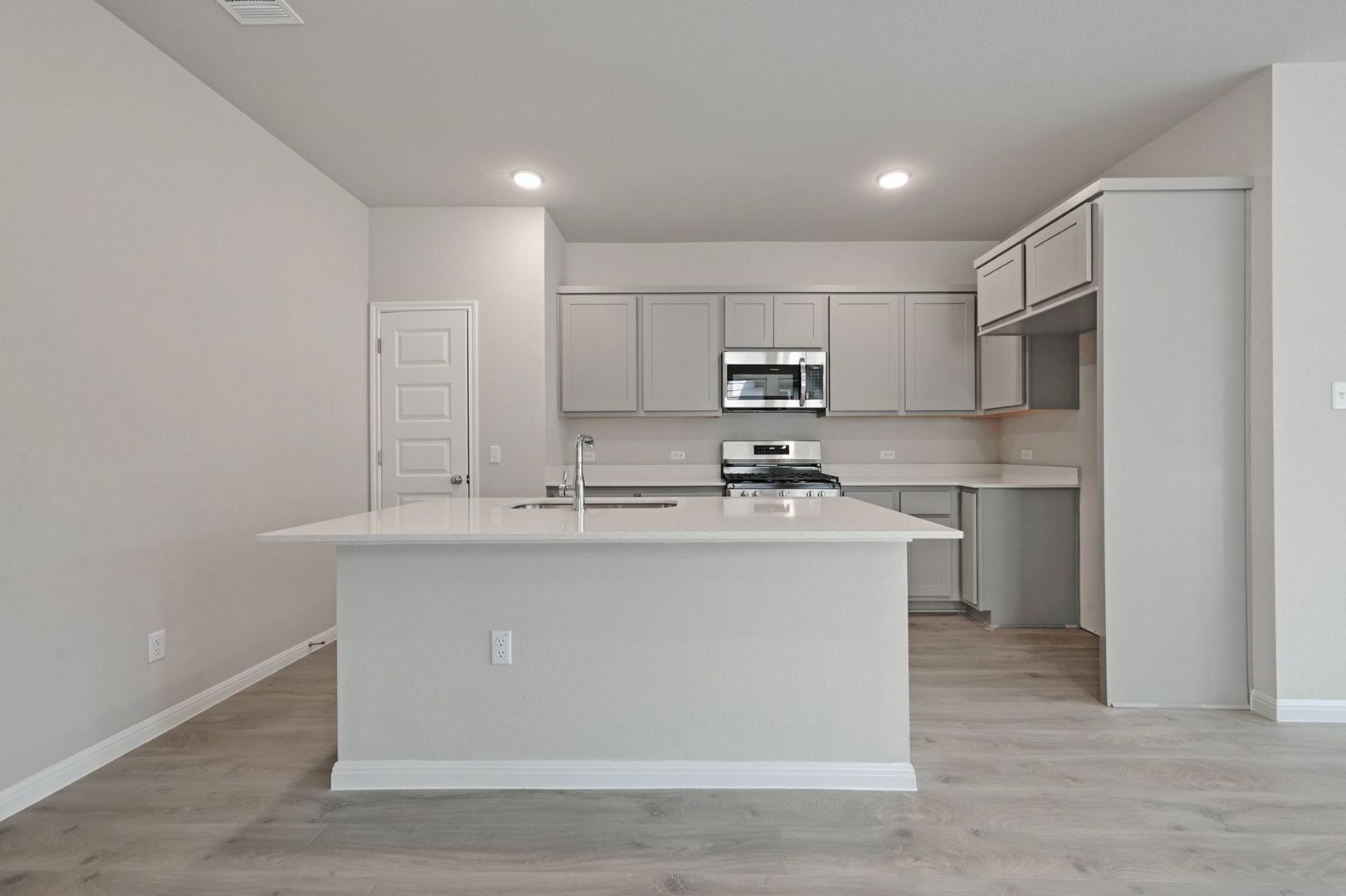 174 Hornet Street Elgin, TX 78621 - Photo 5 of 36 a kitchen with kitchen island a sink a stove a refrigerator and white cabinets