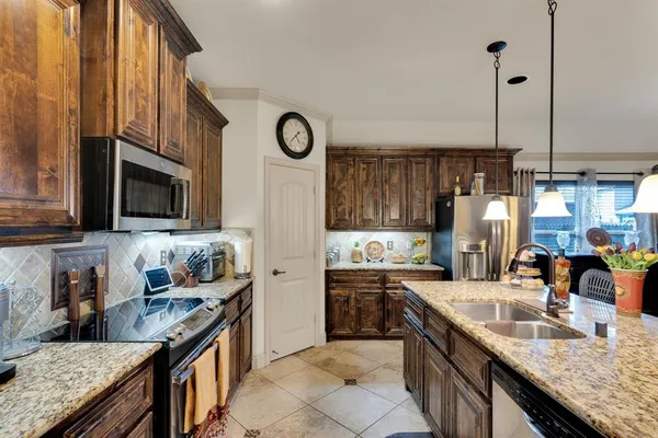 a kitchen with stainless steel appliances granite countertop a stove a refrigerator a oven a sink a dining table and chairs